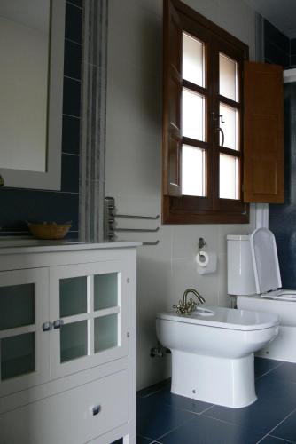 a bathroom with a sink and a toilet and a window at Apartamentos El Valledor in Tremado
