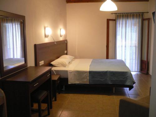 a bedroom with a bed and a desk and a mirror at Megalos Mourtias in Alonnisos