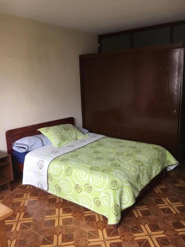 a bed with a green comforter in a room at Hotel Manila Plaza in Bogotá