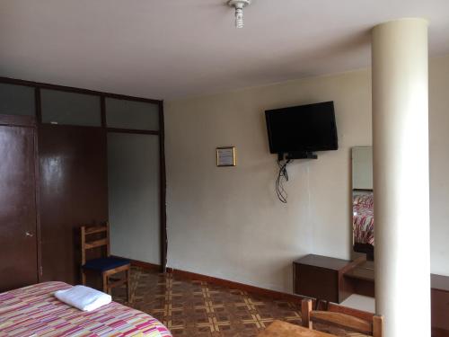 a bedroom with a bed and a tv on the wall at Hotel Manila Plaza in Bogotá