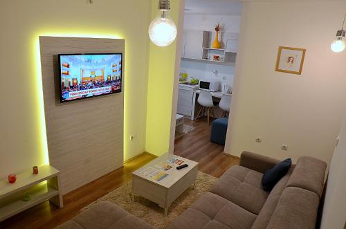 a living room with a couch and a tv on a wall at Lux Apartmani in Kladovo