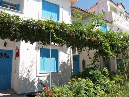 a white house with blue windows and a tree at Pelagia in Marathokampos