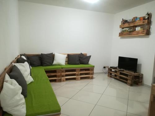 uma sala de estar com um sofá verde e uma televisão em amendola24 em Cefalù