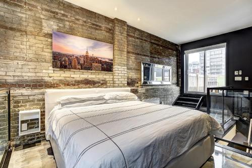 1 dormitorio con cama y pared de ladrillo en Boutique Lofts Milton Parc by Simplissimmo, en Montreal