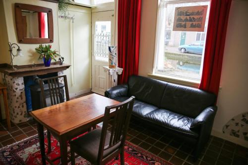 a living room with a leather couch and a table at B&B Gasthuis 288 in Delft