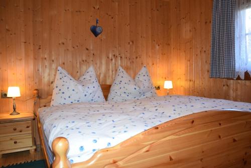 a bedroom with a wooden bed with white sheets and pillows at Untere Roner Kasa in Mörtschach
