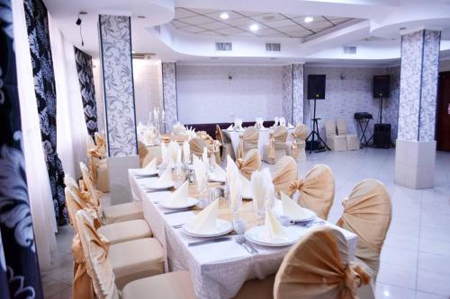 a room with a long table and white chairs at Pensiunea Nicolas in Craiova