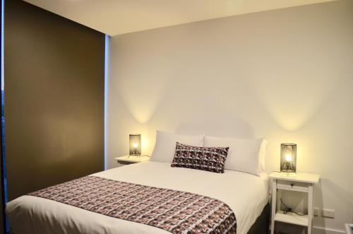 a bedroom with a large bed with two night stands at VUEonKW in Adelaide