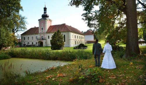 a bride and groom standing in front of a building at Penzion Zámek Lešany in Netvořice