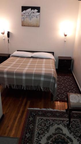 a bedroom with a bed with a plaid blanket at Hostal Santa María Gracia in Quito