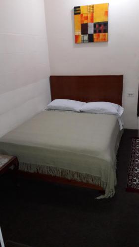 a bedroom with a large bed with a wooden headboard at Hostal Santa María Gracia in Quito