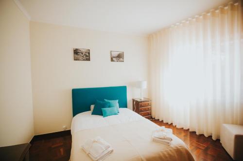 a bedroom with a large white bed with blue accents at Vila Luis Mendes in Ribeira Brava