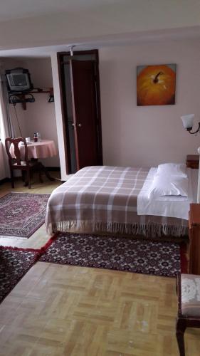 a bedroom with a bed with a plaid blanket at Hostal Santa María Gracia in Quito