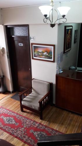 a living room with a chair and a door at Hostal Santa María Gracia in Quito