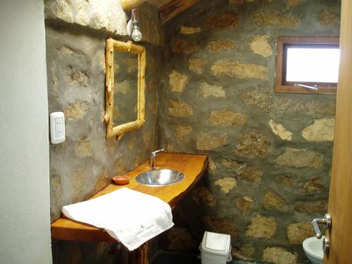 a stone bathroom with a sink and a mirror at Alauri Ñire in Huinganco