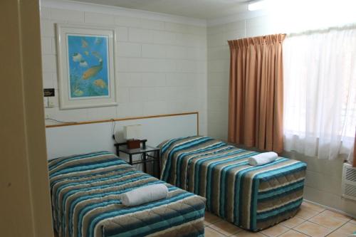 a hotel room with two beds and a window at Oasis Inn Apartments in Cairns