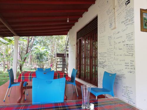 a table and chairs on a porch with writing on the wall at Homely Guest in Habarana