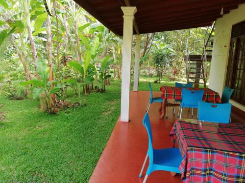 a porch with blue chairs and a table in a yard at Homely Guest in Habarana