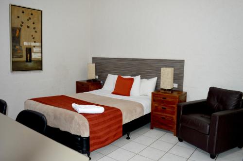 Habitación de hotel con cama y silla en Mid City Motor Inn, en Gladstone