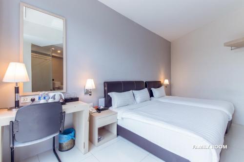 a bedroom with a bed and a desk and a mirror at De Elements Business Hotel KL in Kuala Lumpur