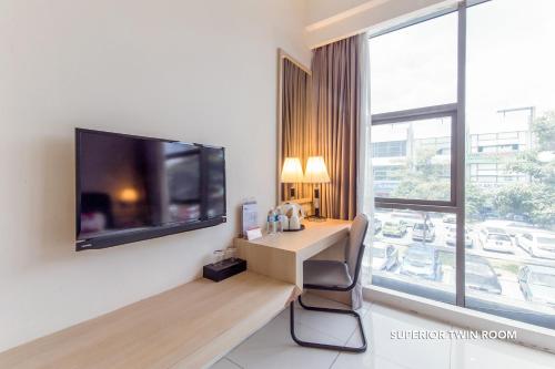 a room with a television and a desk with a chair at De Elements Business Hotel KL in Kuala Lumpur