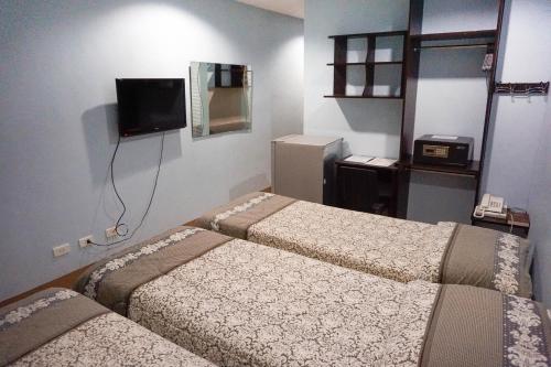 a hotel room with two beds and a television at Crowne Garden Hotel in Cebu City