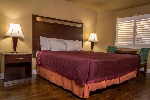 1 dormitorio con 1 cama con colcha roja y 2 lámparas en Crossroads Inn - Downtown Sacramento, en Sacramento