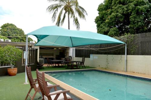 a blue umbrella over a pool with chairs and a table at Mid City Motor Inn in Gladstone