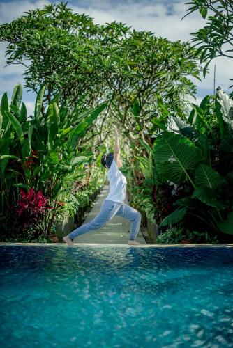 a woman is dancing next to a swimming pool at Rama Residence Petitenget in Seminyak
