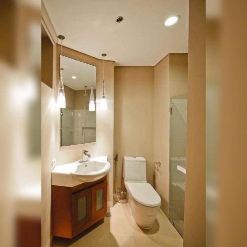 a bathroom with a toilet and a sink and a mirror at Miranda 514B 2br at Pico de Loro by Raquel's Place in Nasugbu