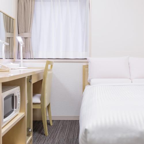 a hotel room with a bed and a desk with a microwave at HOTEL MYSTAYS Higashi Ikebukuro in Tokyo