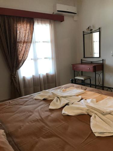a bed with dirty clothes on it with a window at TO VOTSALO-beach side studios & taverna in Karpathos Town