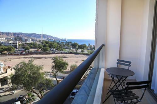 a balcony with a table and chairs looking out at the ocean at Lacosta Hotel in Aqaba