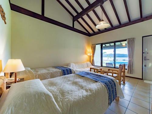 a bedroom with three beds and a view of the ocean at Villa Unarizaki in Iriomote