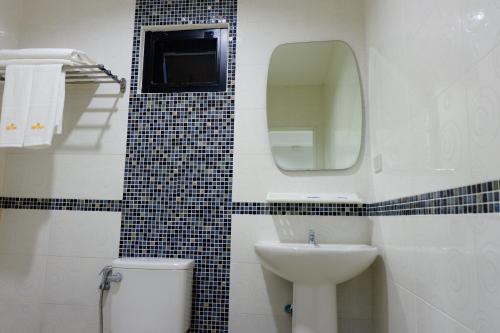 a bathroom with a sink and a toilet and a mirror at The Gun Hotel in Surin