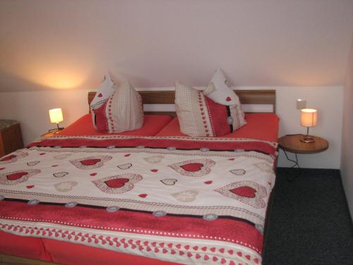 ein Bett mit roten und weißen Decken und Kissen in der Unterkunft Ferienhaus Schrammsteinblick in Bad Schandau