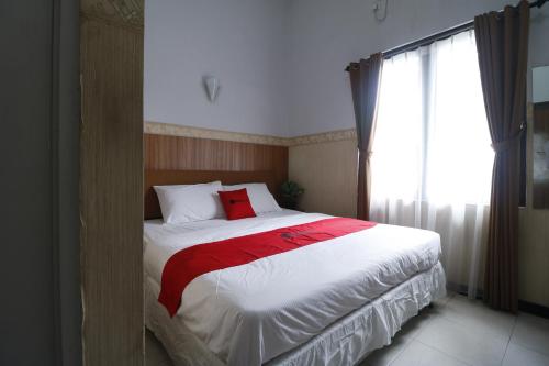 a bedroom with a large bed with a red blanket at RedDoorz Plus near Undip Tembalang in Semarang