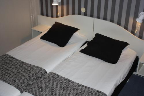 two beds with black and white sheets and pillows at Hotell Angöringen in Karlskrona