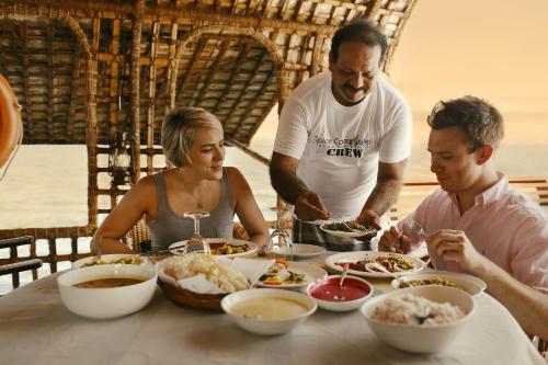 a group of people sitting around a table eating food at Spice Coast Cruises - Houseboat, A CGH Earth Experience in Alleppey