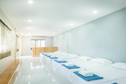 a row of white beds in a room at Ivy Cottage by Qiu in Sara Buri
