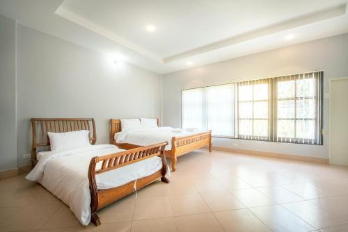 a bedroom with two beds and a large window at Ivy Cottage by Qiu in Sara Buri