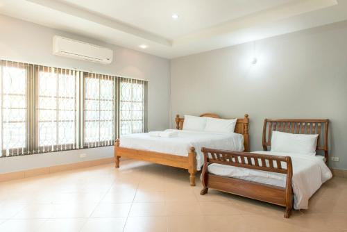 two beds in a room with two windows at Ivy Cottage by Qiu in Sara Buri