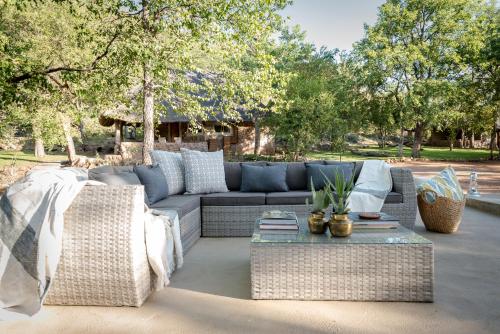 a patio with a couch and a table and trees at Chacma Bush Camp in Balule Game Reserve
