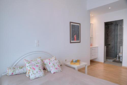 a white bedroom with a bed with pink pillows at Apartment in Glyfada Center in Athens