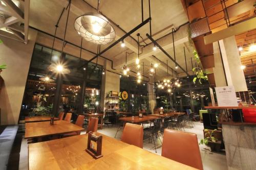a restaurant with wooden tables and chairs and lights at Hay Bandung in Bandung