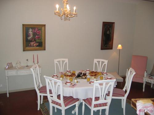 a dining room with a white table and white chairs at Le Clos Xavianne in Ribécourt-la-Tour