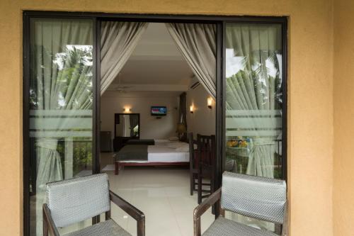 a room with two chairs and a bedroom with a bed at Oruthota Chalets in Kandy