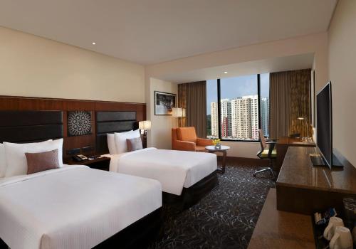 a hotel room with two beds and a television at Novotel Kochi Infopark in Cochin