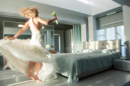 a woman in a white dress jumping on a bed at The Majestic Hotel in Fira