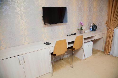 a desk with two chairs and a television on a wall at Stary Gorod Hotel in Kazan